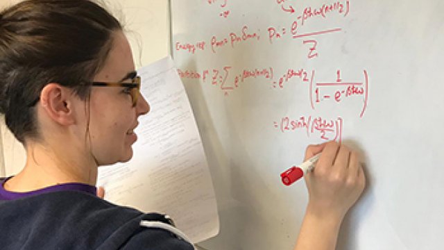 A student writing an equation on a white board
