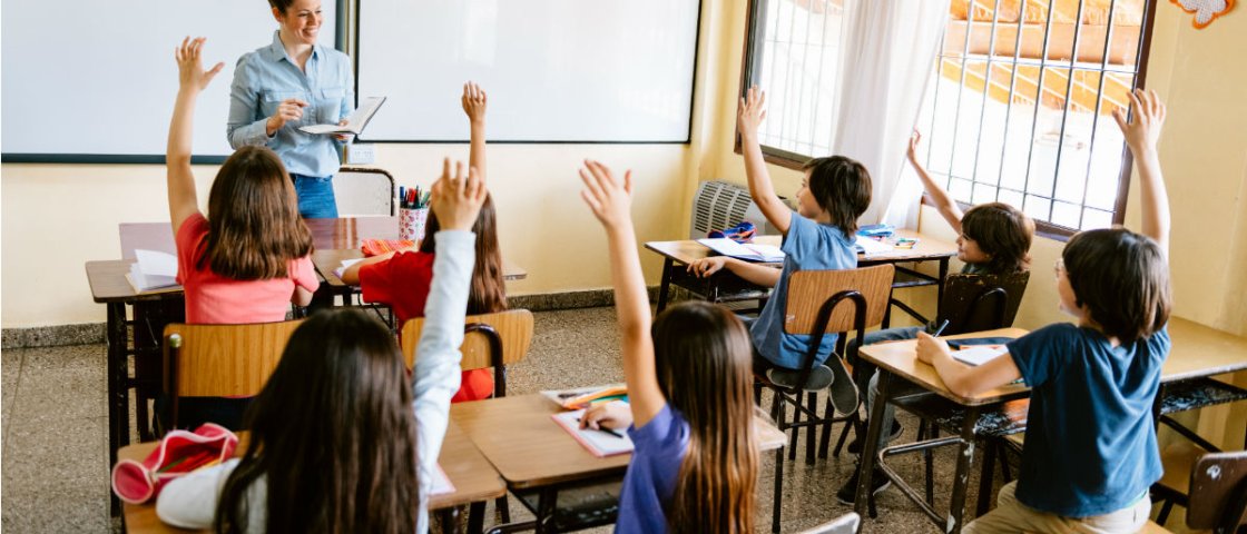 School children with their hands up in classroom