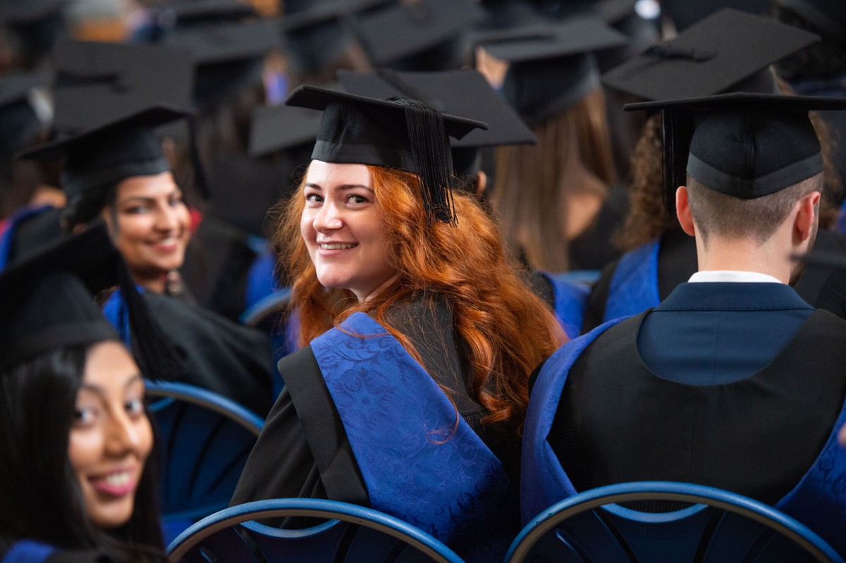 Surrey graduand turning around in graduation ceremony audience