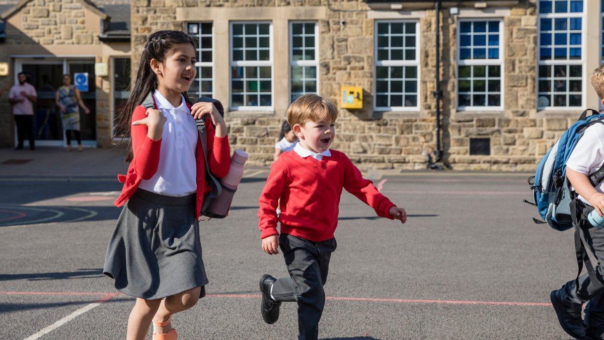 two children run across a primary school playground