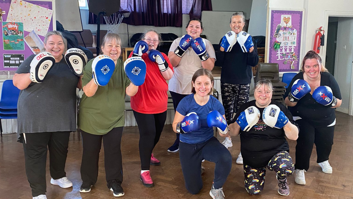 Women pose with boxing gloves during exercise class