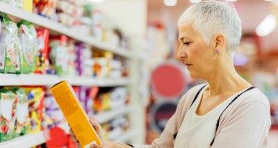 Lady reading health information on a packet of food in the supermarket