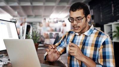 Male talking into headphones looking at laptop