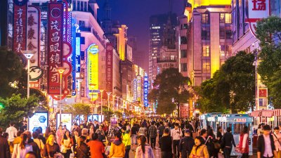 A city at night lit up with lots of people walking around