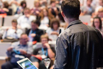 Lecturer stands in front of crowded lecture hall