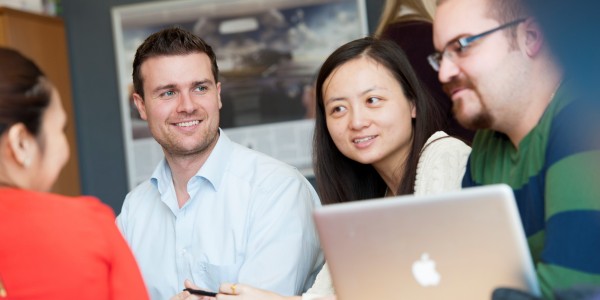 Four Surrey Executive MBA students sitting around a laptop