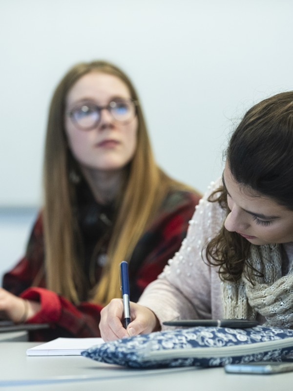 two female students writing on their notebooks