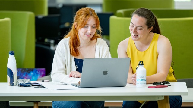 Two students looking at a laptop together