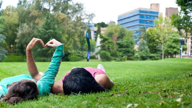 Students on grass with hands in hearts