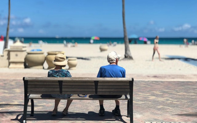 Older man and woman on a bench looking at the beach