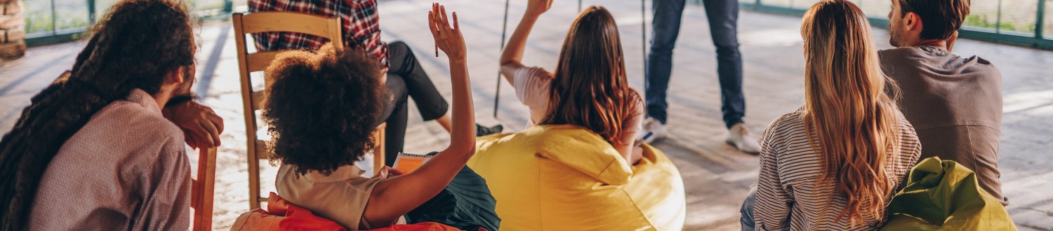 People sitting on bean bags with hands raised.