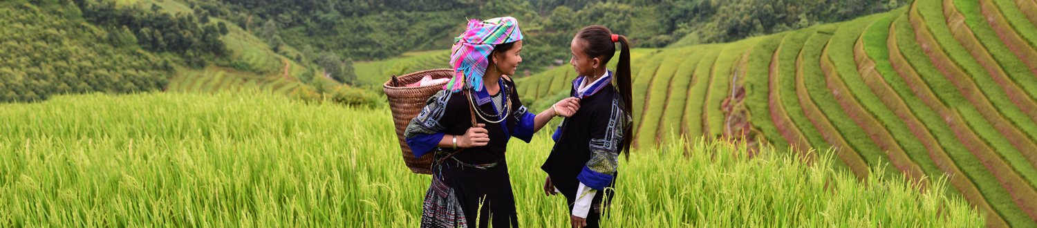 Two women talking with green fields surrounding them