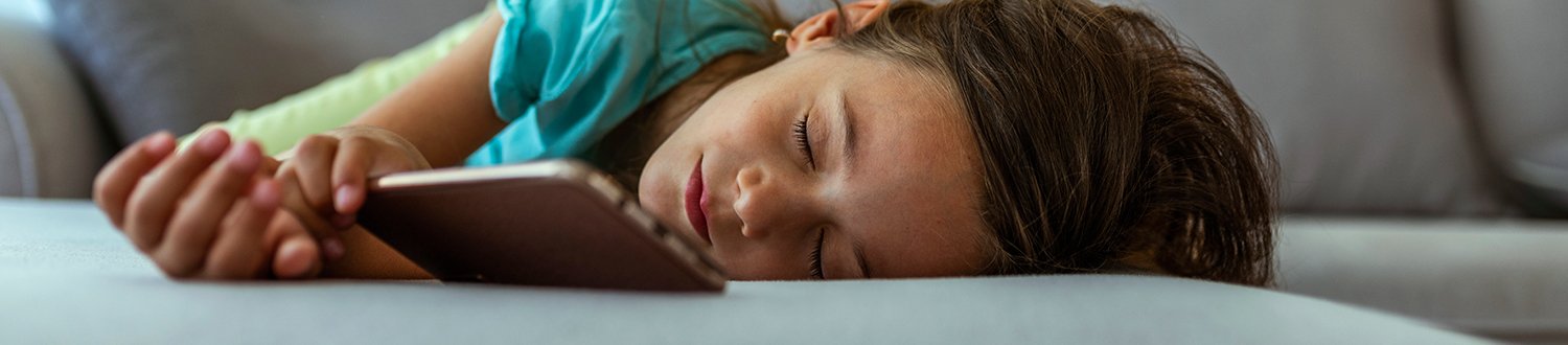 A young girl is asleep in front of her mobile phone