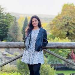 Ganguli smiling to the camera in front of a woodland area.