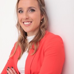 Headshot of Jasmine Bone, arms crossed and wearing an orange suit