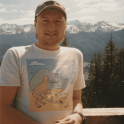 Jonny standing in front of mountains and trees.