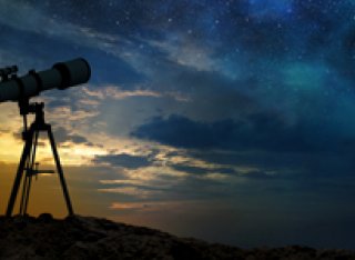 Telescope on hill at night with stars shining