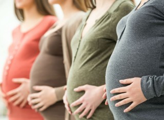 Pregnant women standing in a row holding their bellies