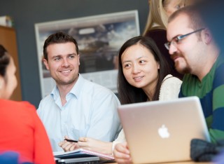 Four Surrey Executive MBA students sitting around a laptop