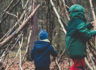 Two small children building a den in the woods