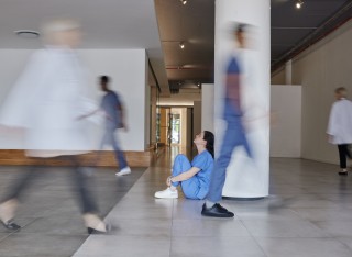 GettyImages - Nurse sitting on the floor while people walk by