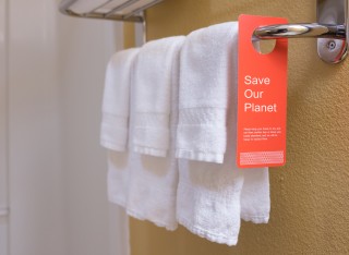 Towels on rack with notice to improve sustainablity by not too regularly washing them