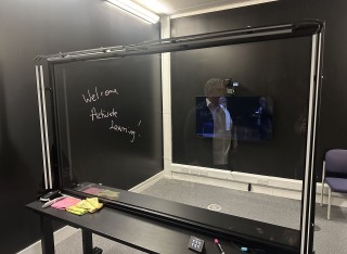 A hand-written welcome to Active Learning notice on a digital board for its visit to the University of Surrey