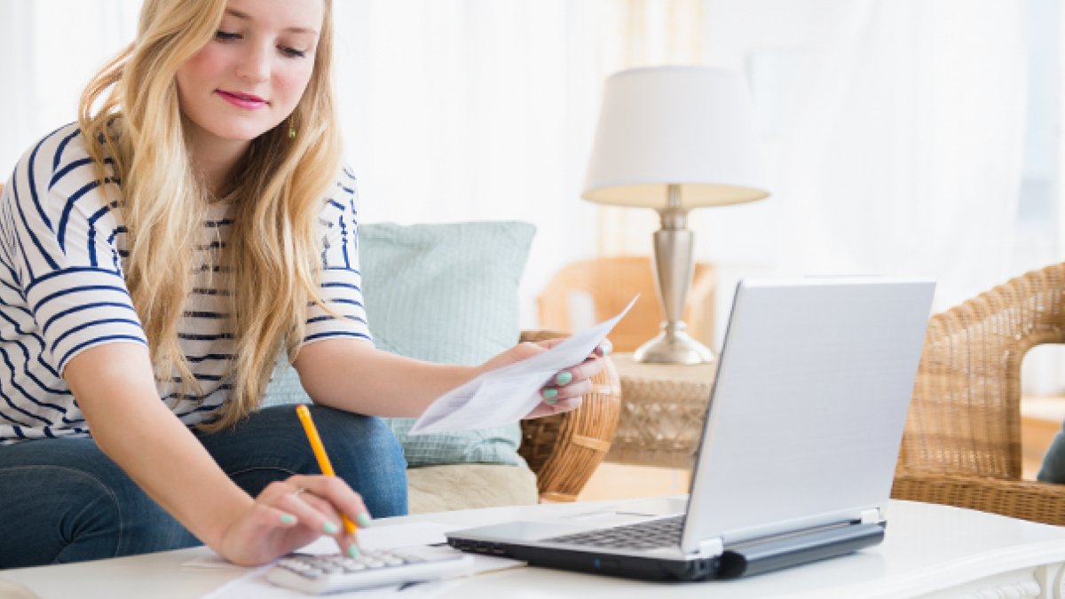 Student on calculator sat at laptop