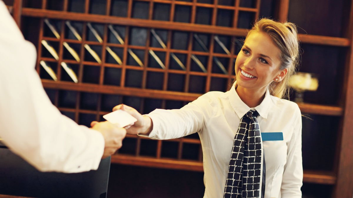 A lady serves a hotel guest on reception