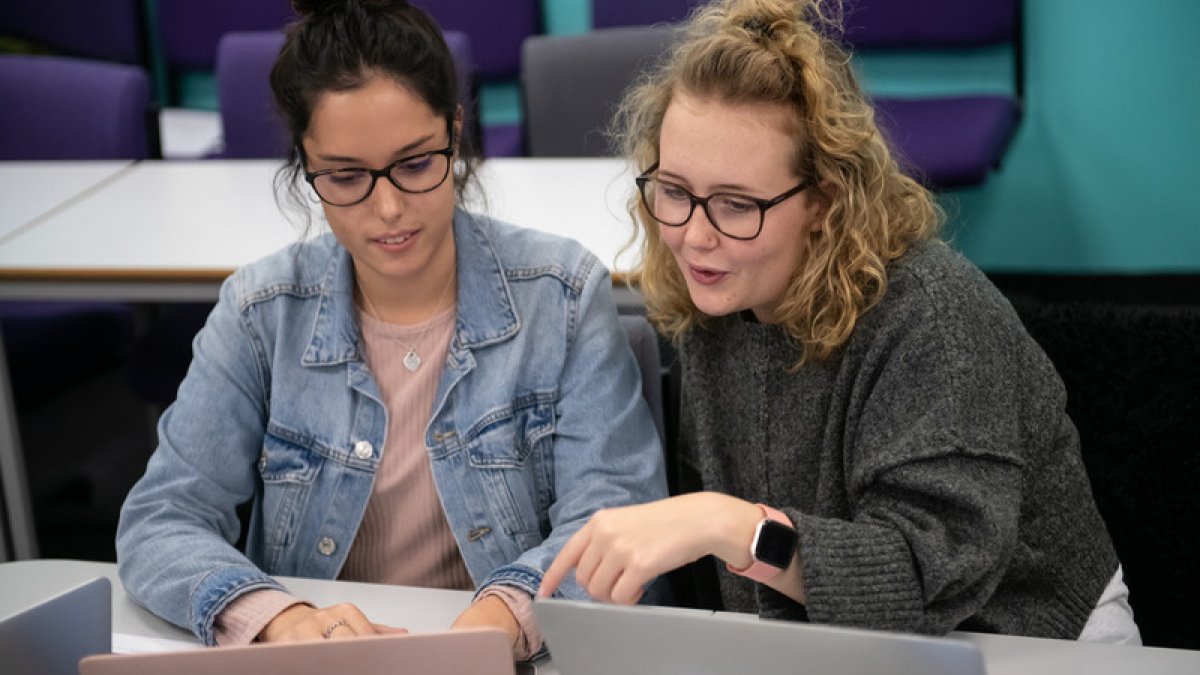 Students looking at a laptop in a psychology lecture