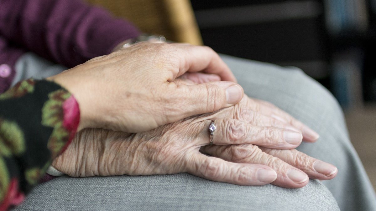 Carer holding hand of an elderly woman