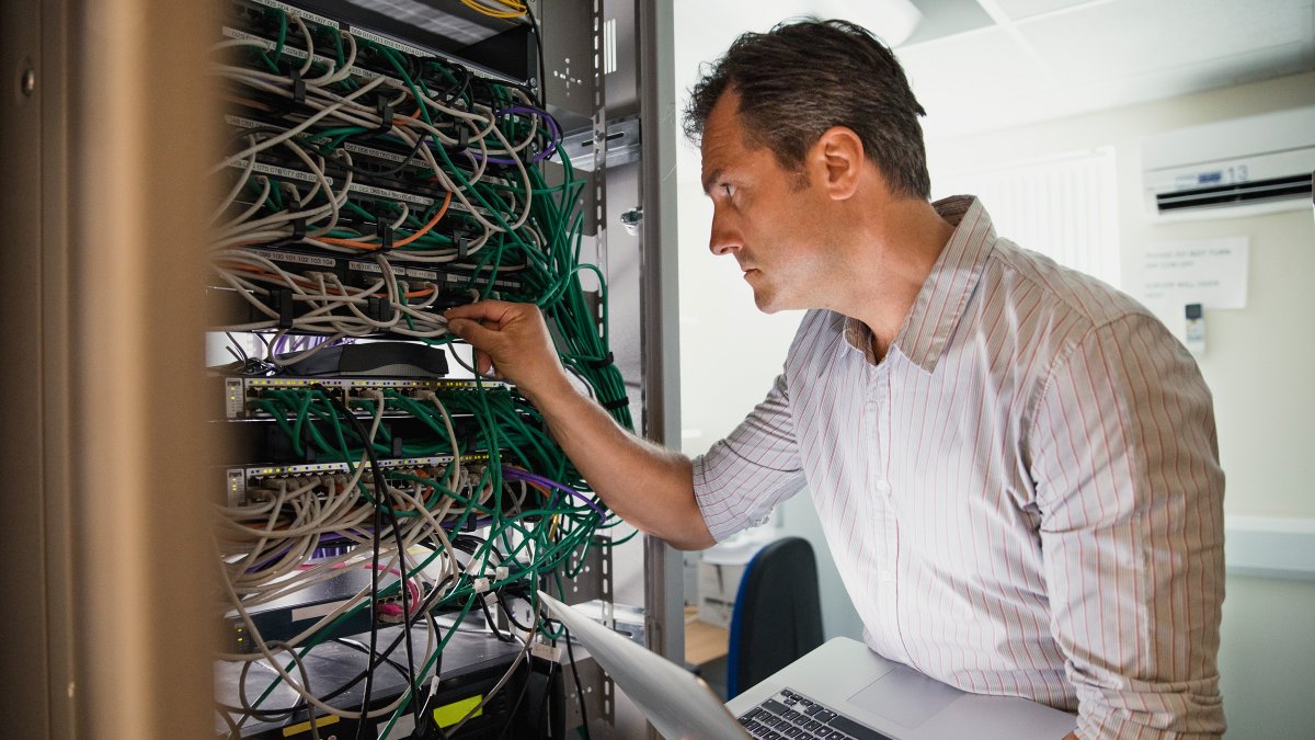 IT technician standing next to data bank