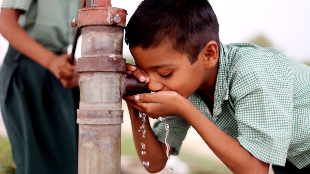 Boy drinking water from a pump