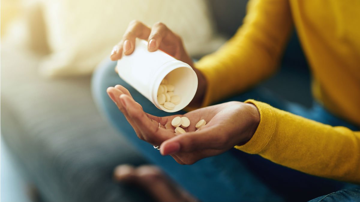 Person putting tablets from bottle into their hand