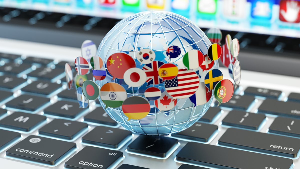 World globe with several country flags around it, sitting on top of a laptop keyboard