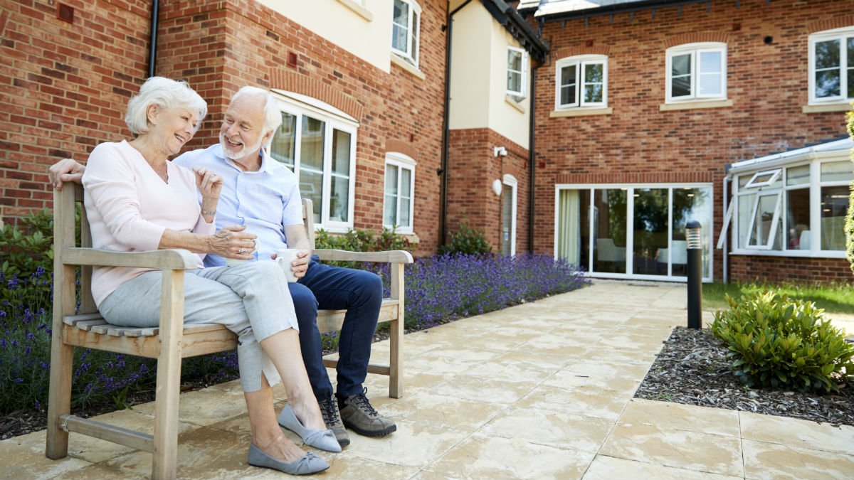 An elderly couple sat on a bench outside