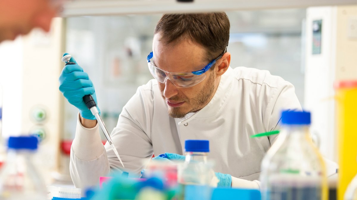 Student in a lab coat using a pipette