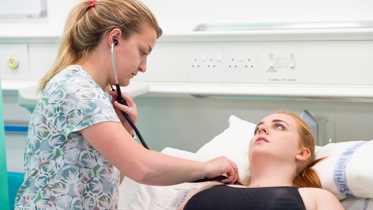 Student checking chest of patient using stethoscope