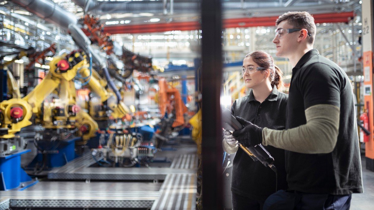 People observing a robotic production line in a car factory