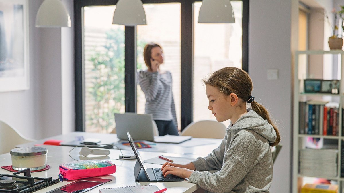 Girl studying at home in the kitchen whilst mum works from home