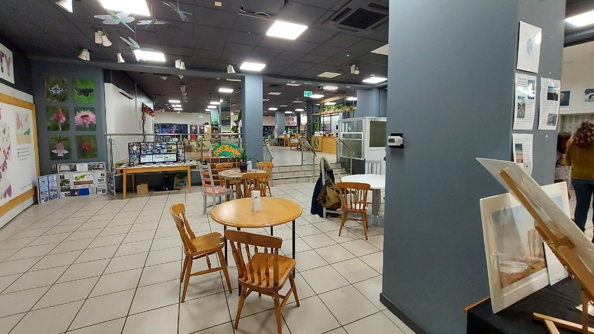 Chairs, tables and displays in a lit room, which is ZERO. On a vertical wall a small air quality monitor can be seen