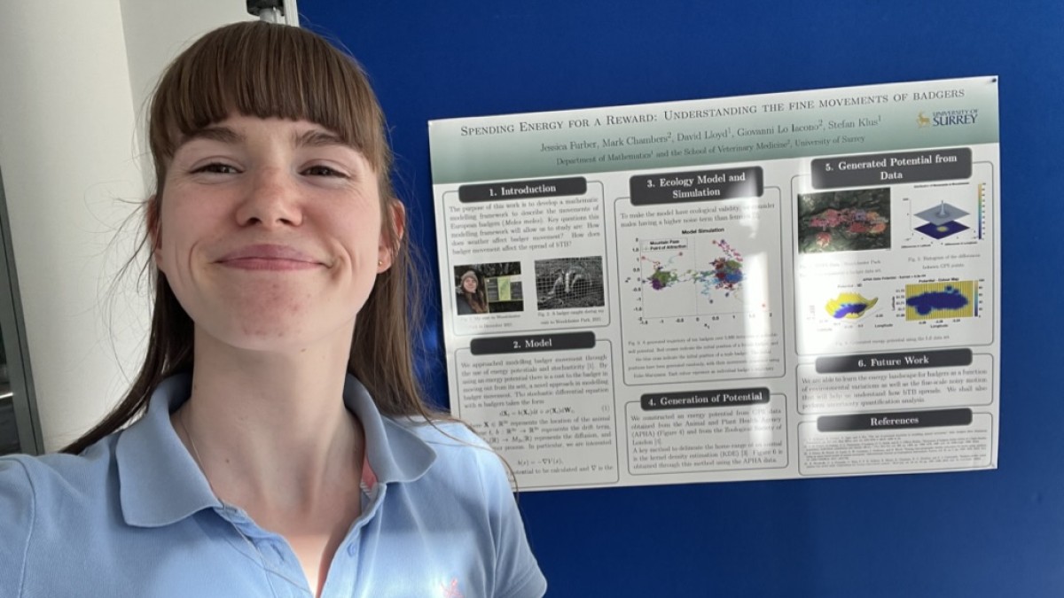 Jessica stands before a board that depicts her research.