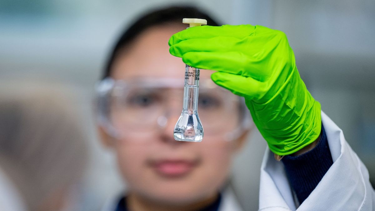 A Pharmaceutical Sciences student in bright green gloves holds up a sample