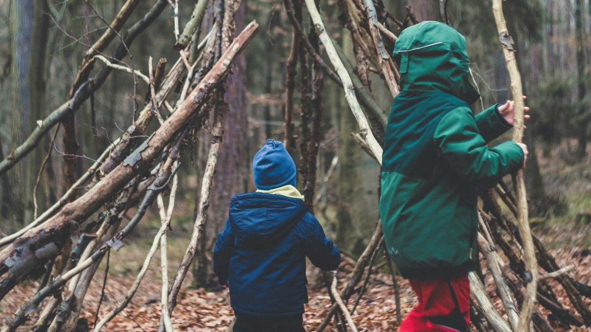 Two small children building a den in the woods