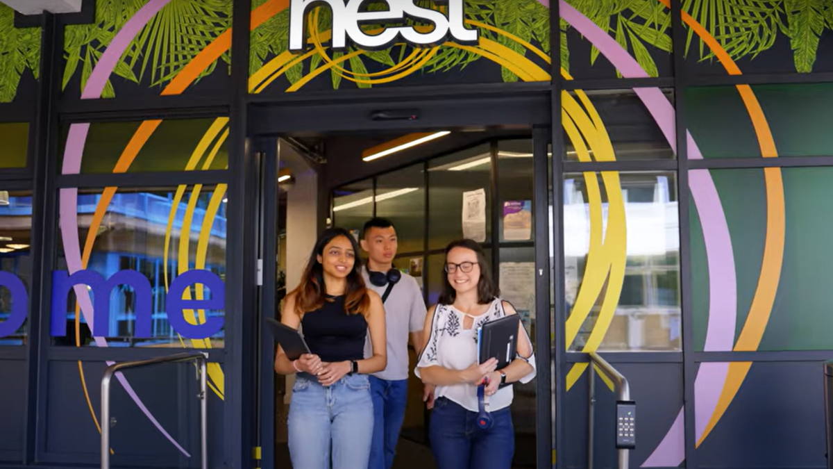 three students exiting the colourful front of the Nest