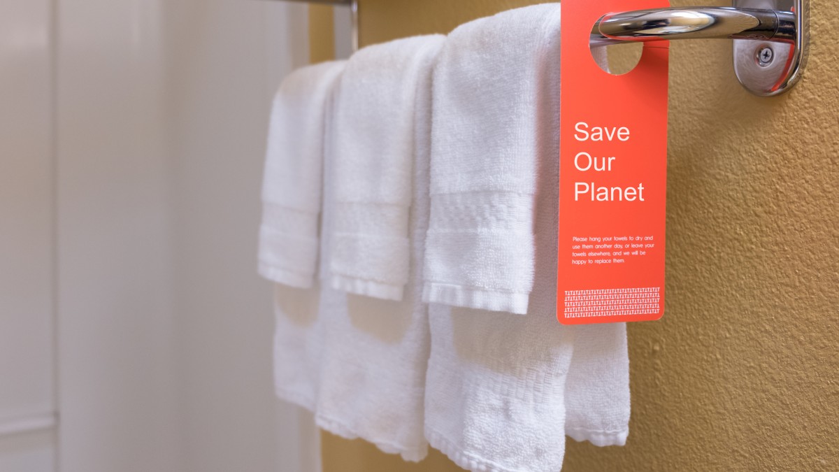 Towels on rack with notice to improve sustainablity by not too regularly washing them